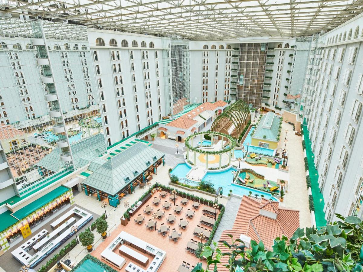Hotel Grand Nikko Tokyo Bay Maihama Urayasu Exterior foto The photo depicts a large indoor area, likely within a resort or hotel, featuring a spacious atrium. The atrium has a glass roof, allowing natural light to flood the space. In the center, there are various swimming pools and a lush, green landscape w