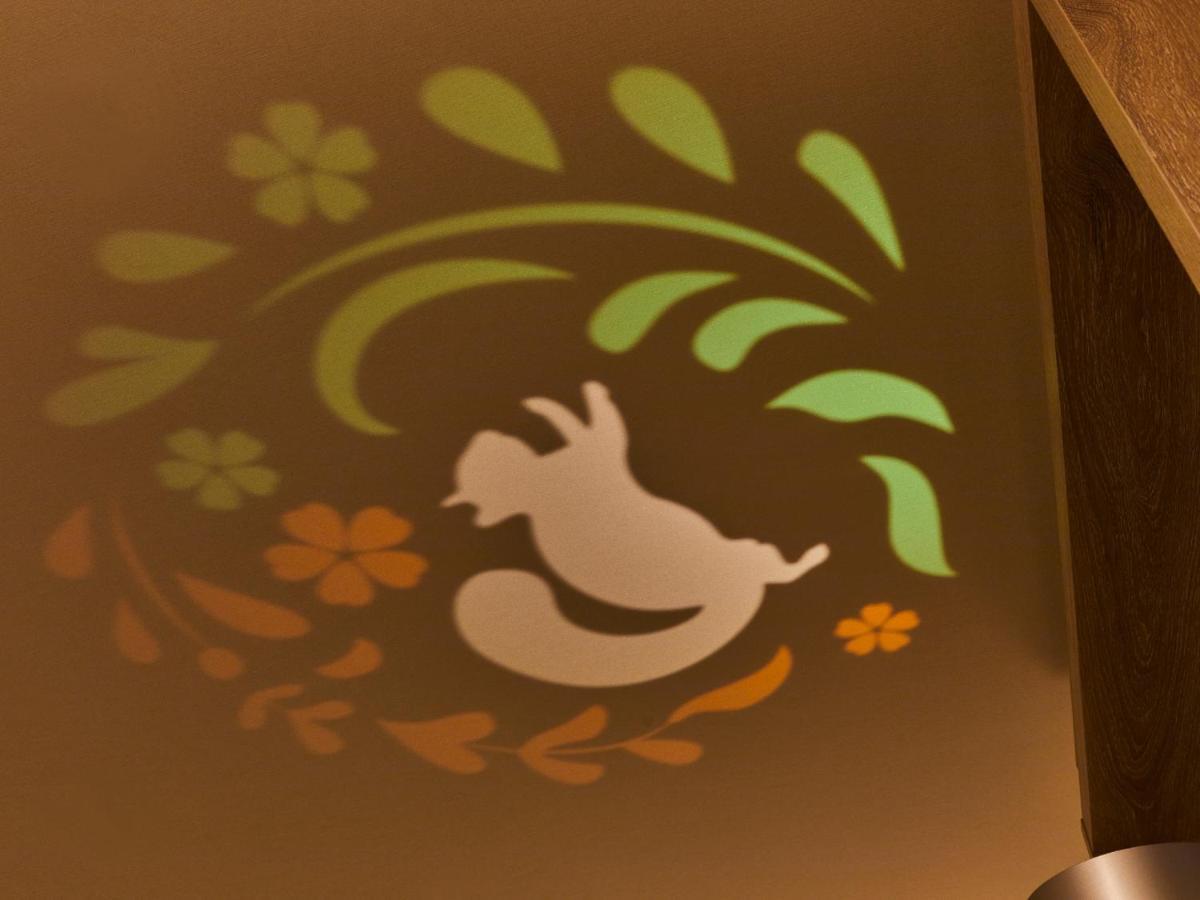 Hotel Grand Nikko Tokyo Bay Maihama Urayasu Exterior foto The photo shows a colorful projection on a surface that includes a playful illustration. The design features a white silhouette of a squirrel in a lively pose, surrounded by decorative elements like green leaves and flowers in shades of orange and ye