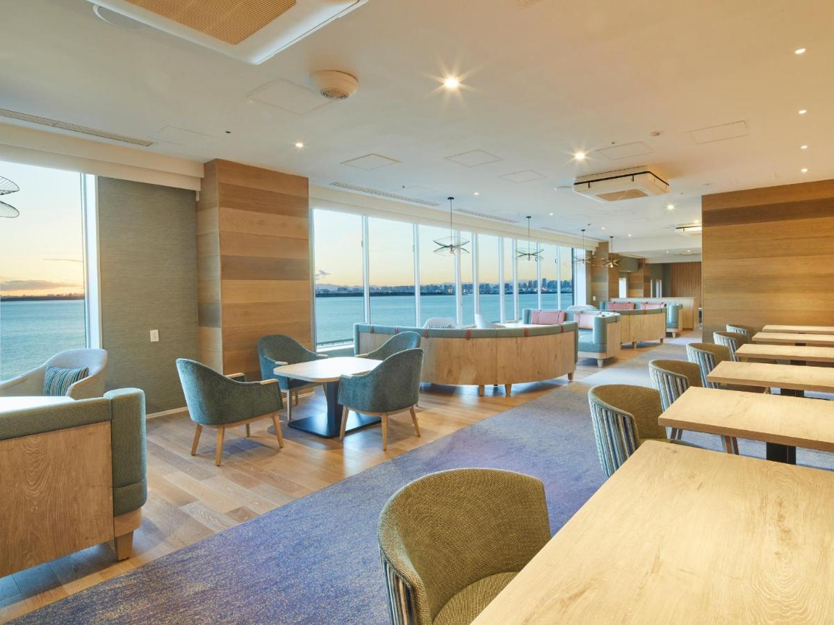 Hotel Grand Nikko Tokyo Bay Maihama Urayasu Exterior foto The photo shows a modern interior space, likely a dining or lounge area. It features large windows that offer a view of the water, allowing natural light to fill the room. The decor includes wooden walls and stylish, comfortable furniture, with sever