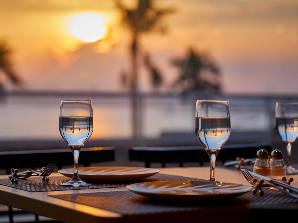 Hotel Grand Nikko Tokyo Bay Maihama Urayasu Exterior foto The photo depicts a picturesque dining setting at sunset. In the foreground, there are two elegantly arranged tables, each set with plates and glasses filled with water. The glasses are crystal clear, reflecting the warm colors of the sunset. Behind 