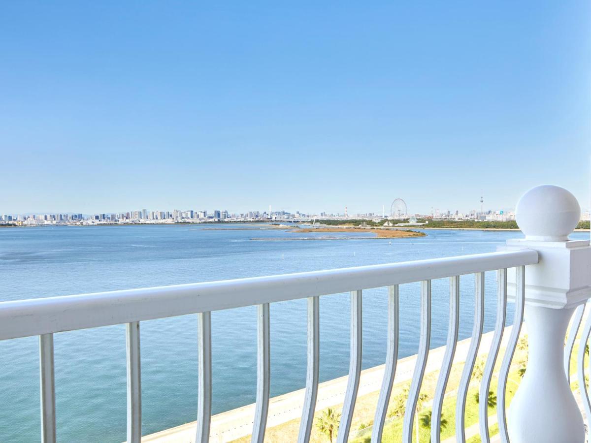Hotel Grand Nikko Tokyo Bay Maihama Urayasu Exterior foto The image shows a view from a balcony overlooking a body of water. In the foreground, there is a white railing that adds depth to the scene. Beyond the railing, you can see calm water reflecting the sky, which is clear with a few faint clouds. In the