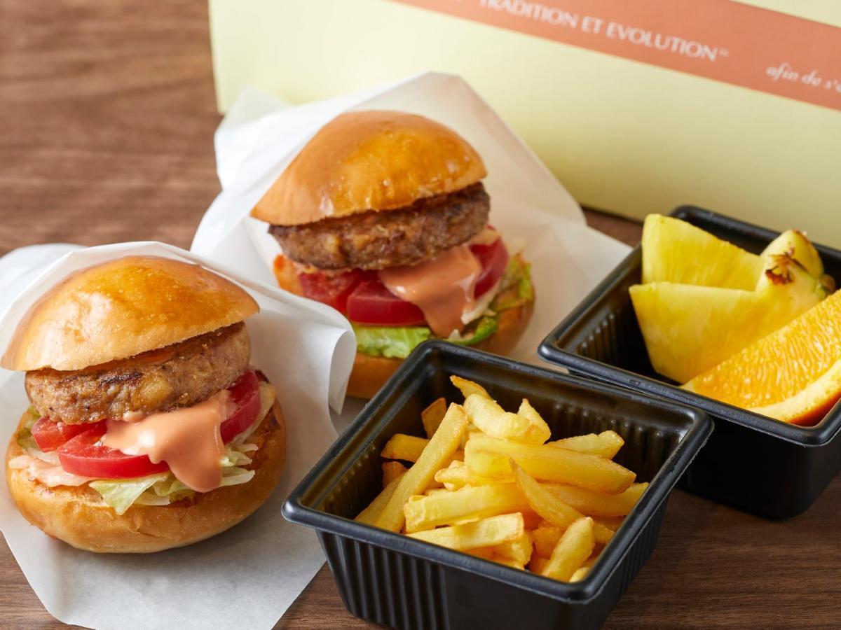 Hotel Grand Nikko Tokyo Bay Maihama Urayasu Exterior foto The photo shows two small burgers placed on a white background, each with a golden-brown bun, a fried patty, lettuce, tomato, and a creamy sauce. Alongside the burgers, there are two containers: one holding a serving of french fries and the other con