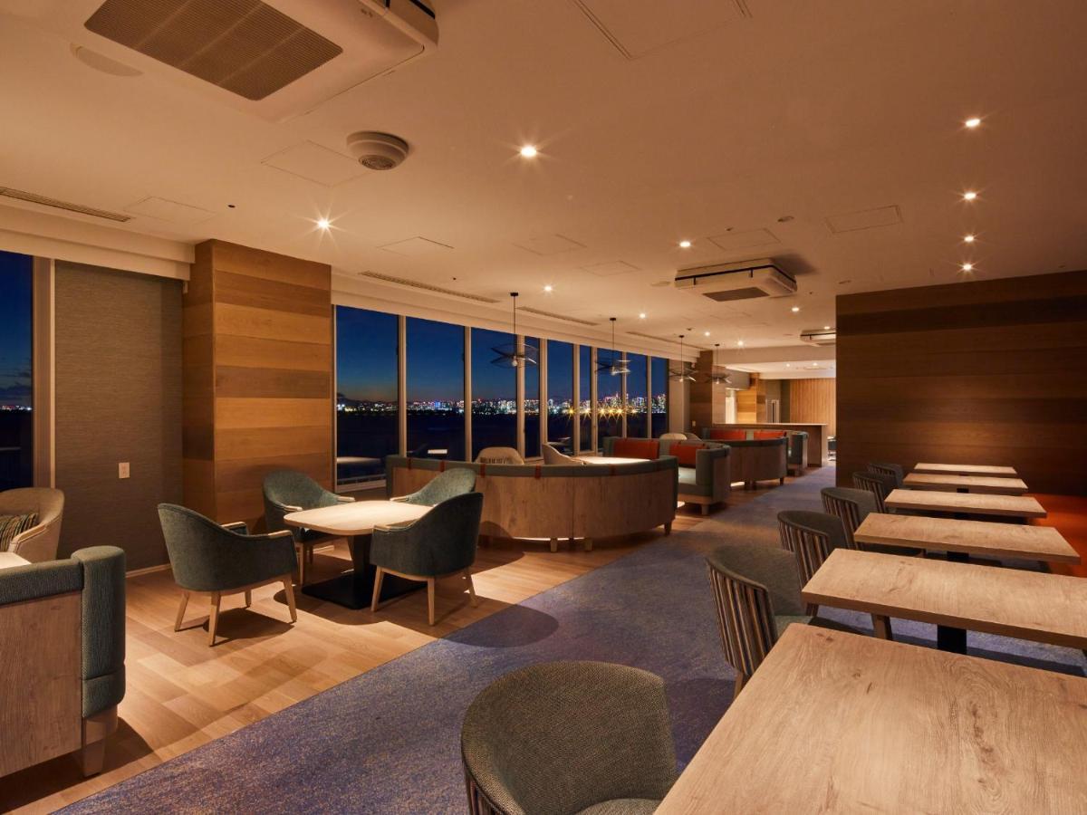 Hotel Grand Nikko Tokyo Bay Maihama Urayasu Exterior foto The photo shows a modern, well-lit lounge or café area. It features a mix of seating options, including cozy armchairs and tables with chairs. The space has large windows displaying a view, likely of a city or landscape at dusk, given the nighttime a