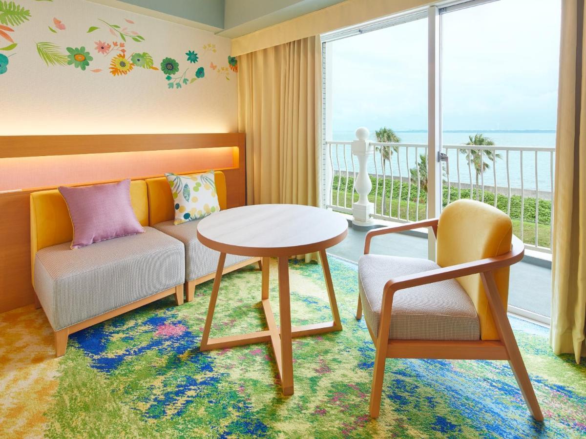 Hotel Grand Nikko Tokyo Bay Maihama Urayasu Exterior foto The photo shows a cozy interior space, likely a hotel room or a lounge area. It features a small round table in the center surrounded by comfortable seating. There are two chairs: one is a light wooden frame with a yellow seat, and the other has a mo