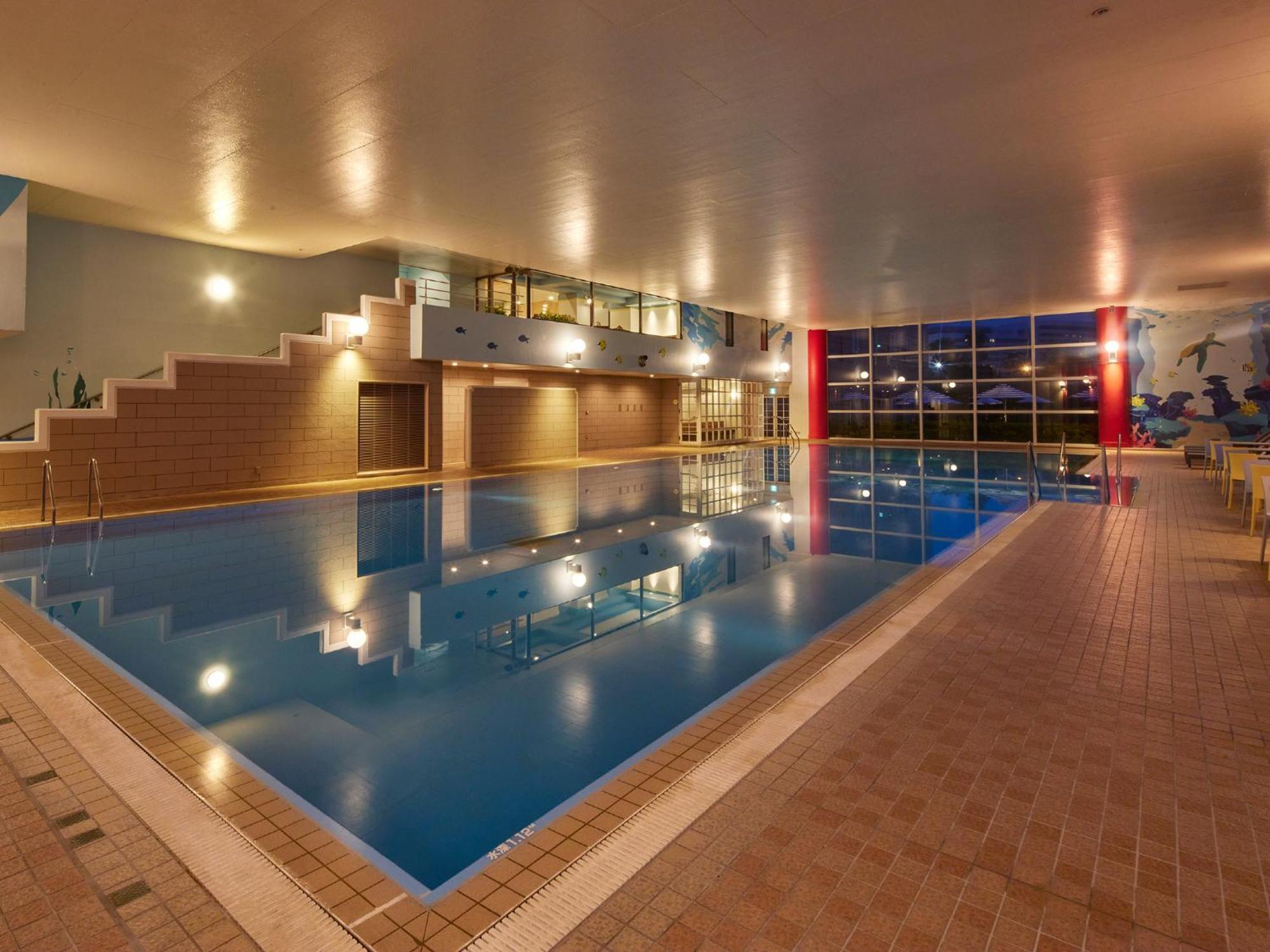 Hotel Grand Nikko Tokyo Bay Maihama Urayasu Exterior foto The photo shows an indoor swimming pool area. The pool features a calm blue water surface and is surrounded by tiled flooring. There is a staircase leading to a higher level, likely providing access to a lounge or seating area. Large windows allow na